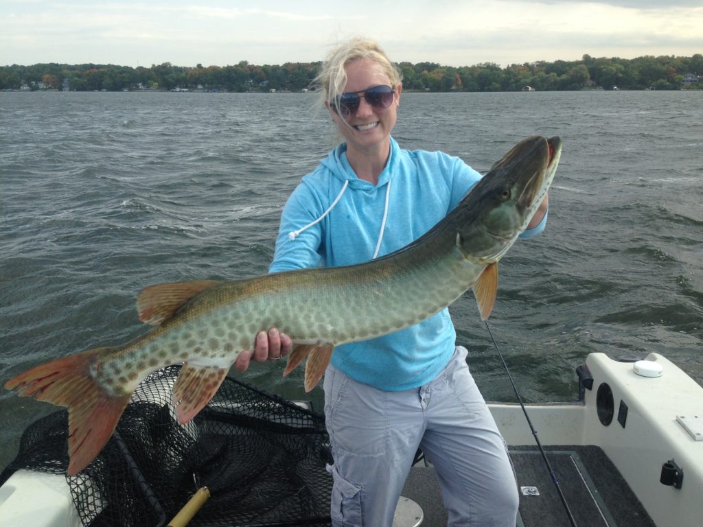 woman holding muskie in a boat
