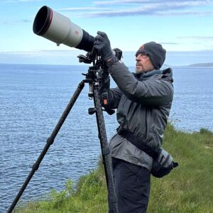 Photographer Peter Cavanagh looking into his camera with large scope
