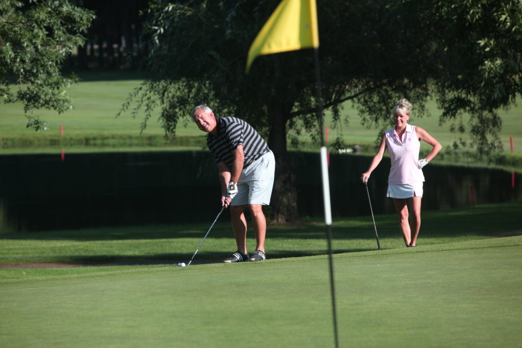 Man putting ball while lady watches on golf cours