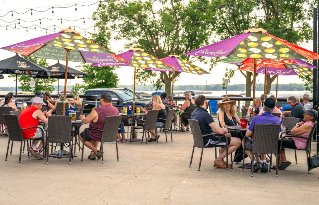 People dining on outdoor patio with a view of Little Detroit Lake