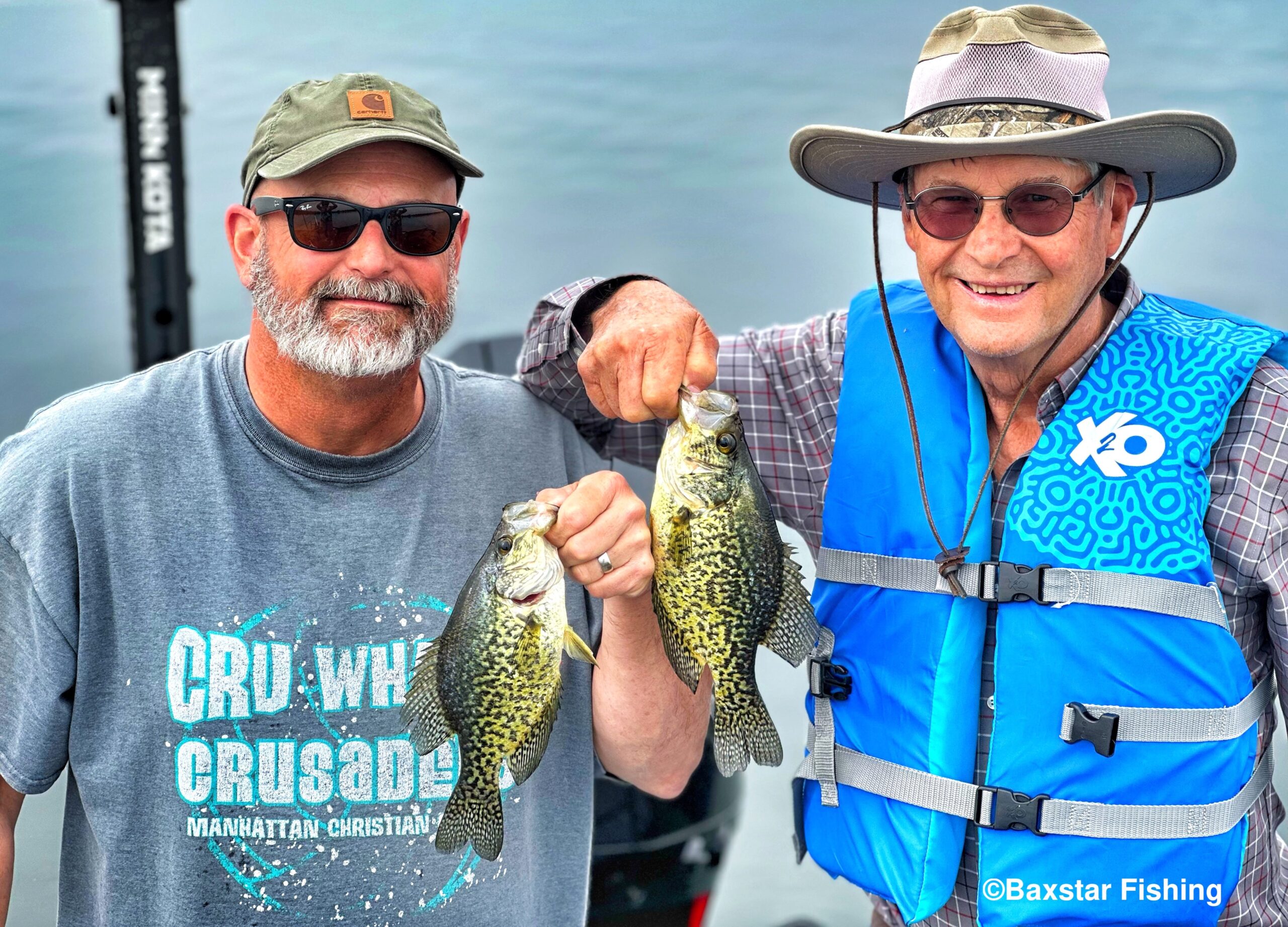 Two fishermen hold up panfish they caught fishing in a boat