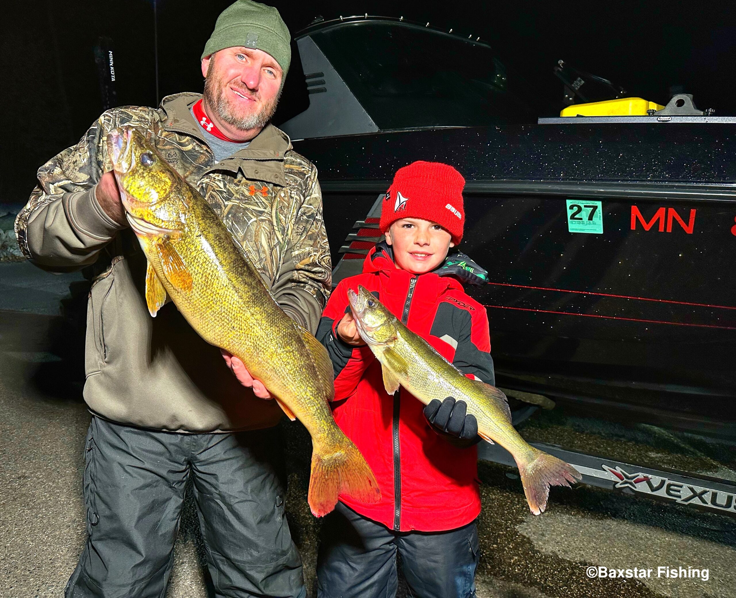 Man and boy holding up good-sized walleyes as dusk rolls in