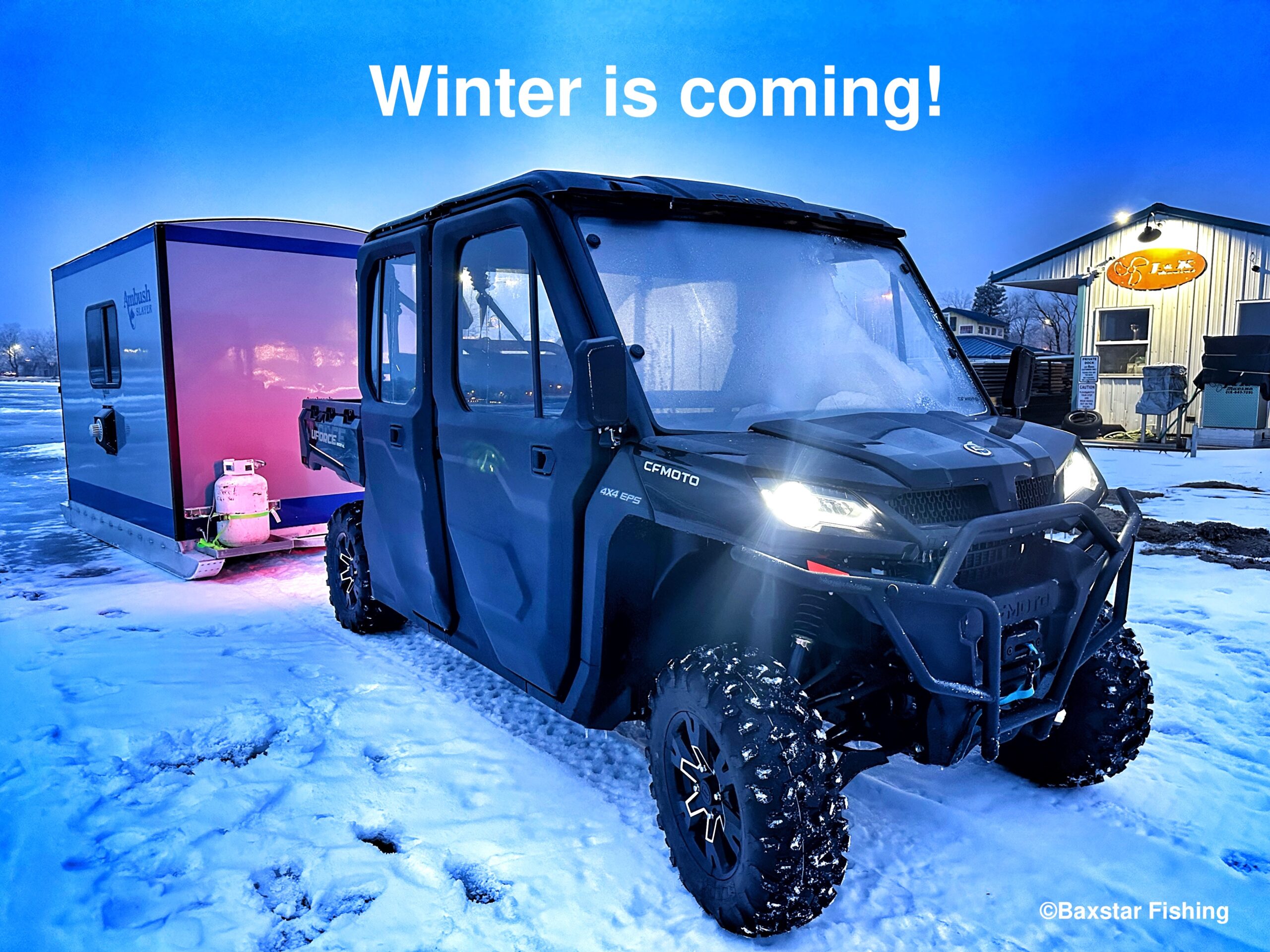 Side by side pulling an ice fishing house on the lake