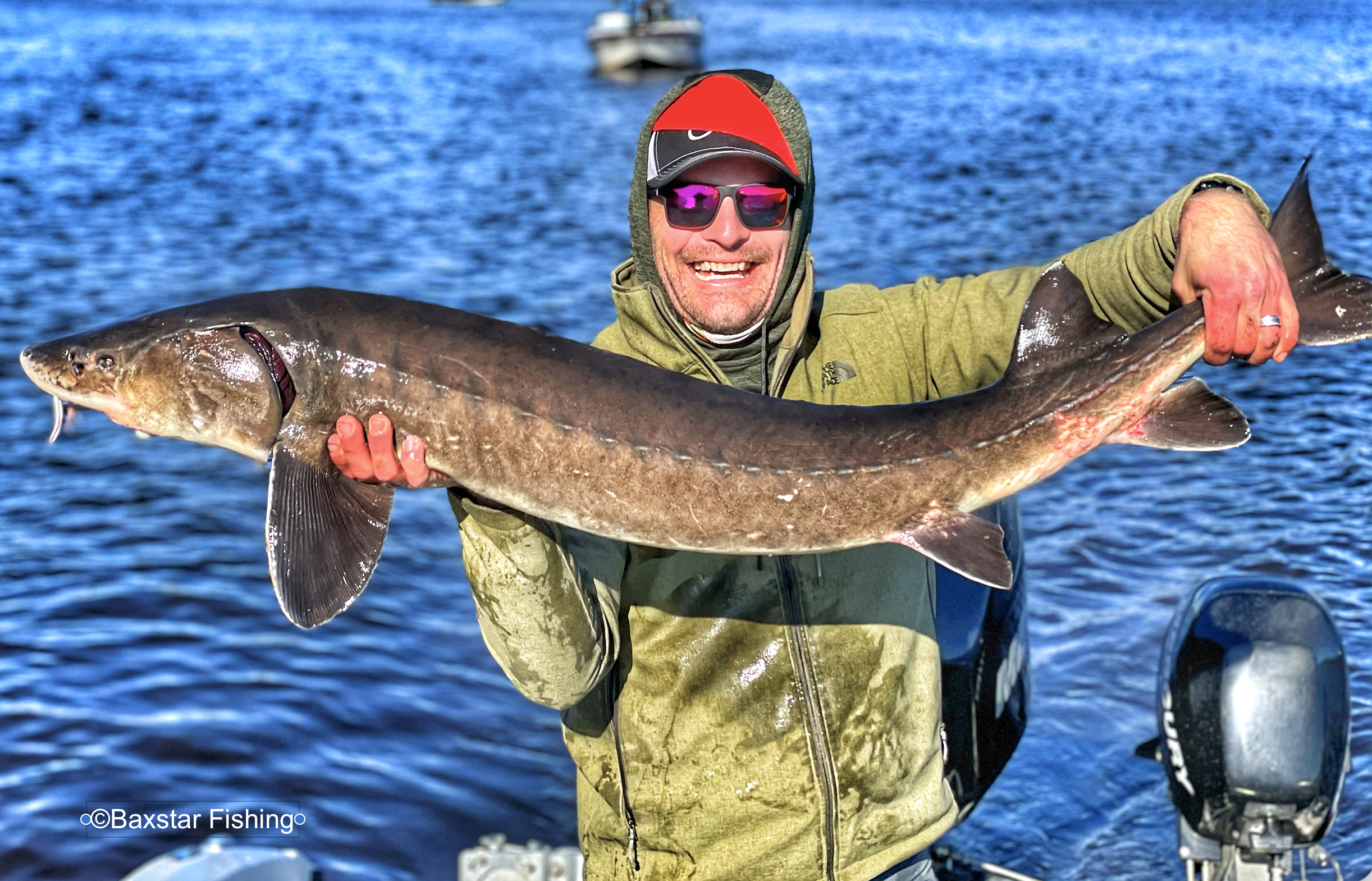 man holding a huge sturgeon caught on Rainy River