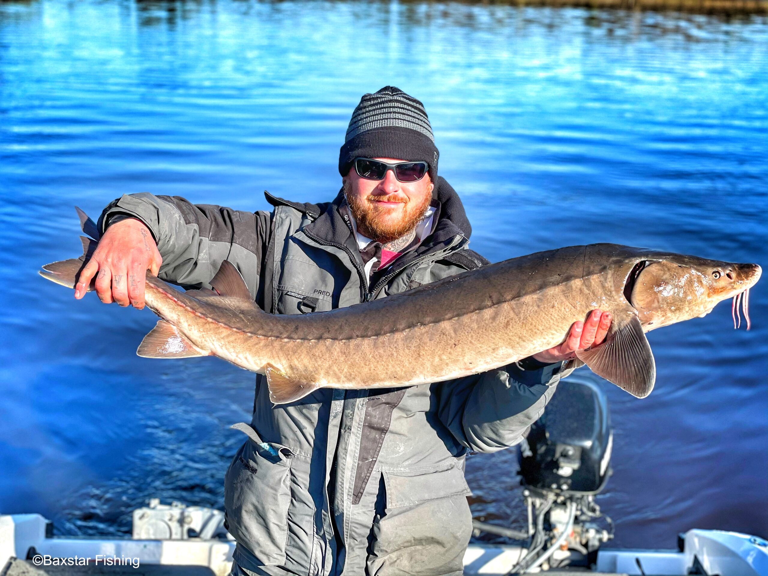man holding a big sturgeon fish caught on Rainy River