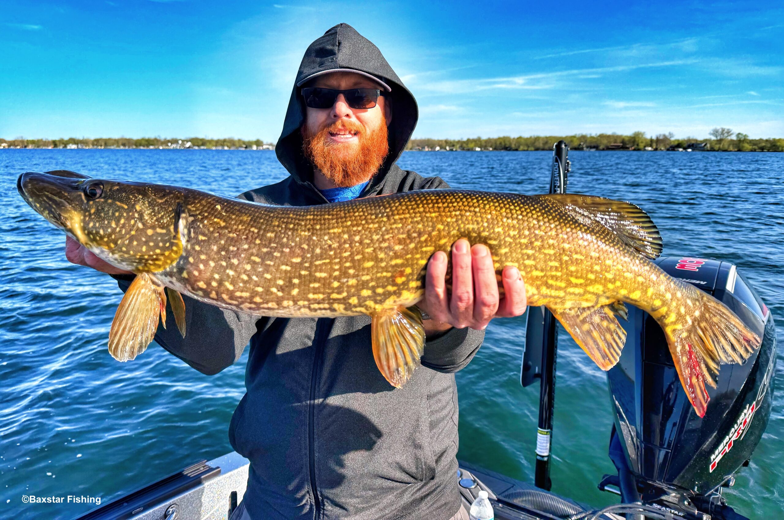man holding a large northern pike he caught while fishing on a lake