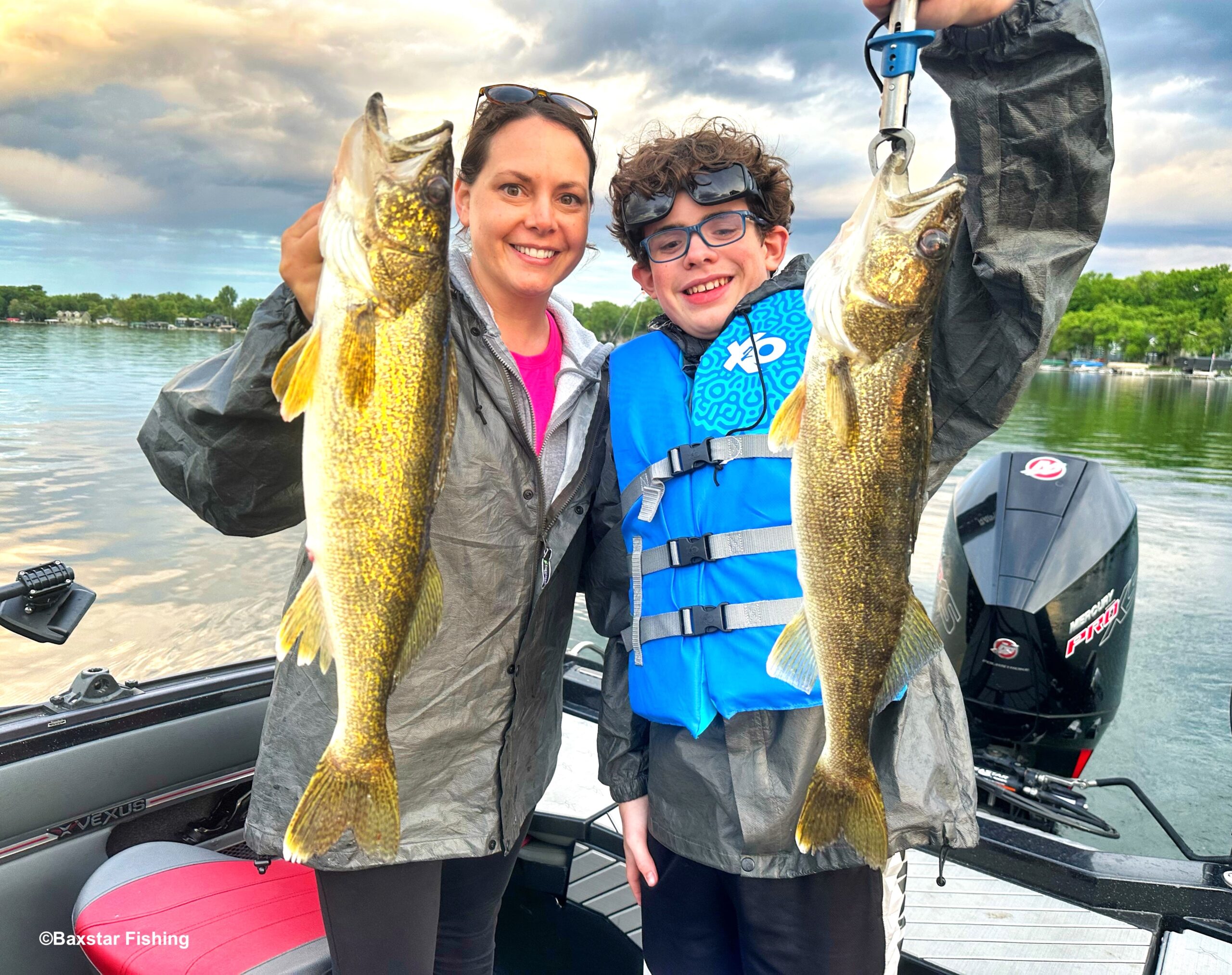 Lady and boy holding up two fish they caught in boat on lake