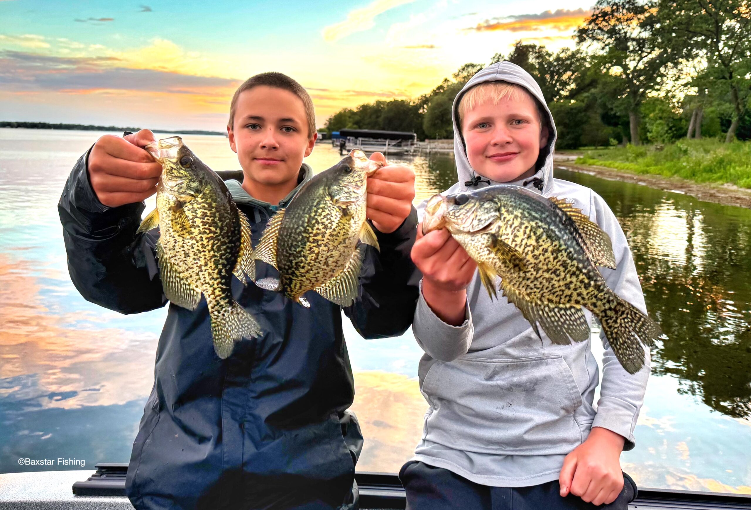 two boys in a boat holding three nice crappies 
