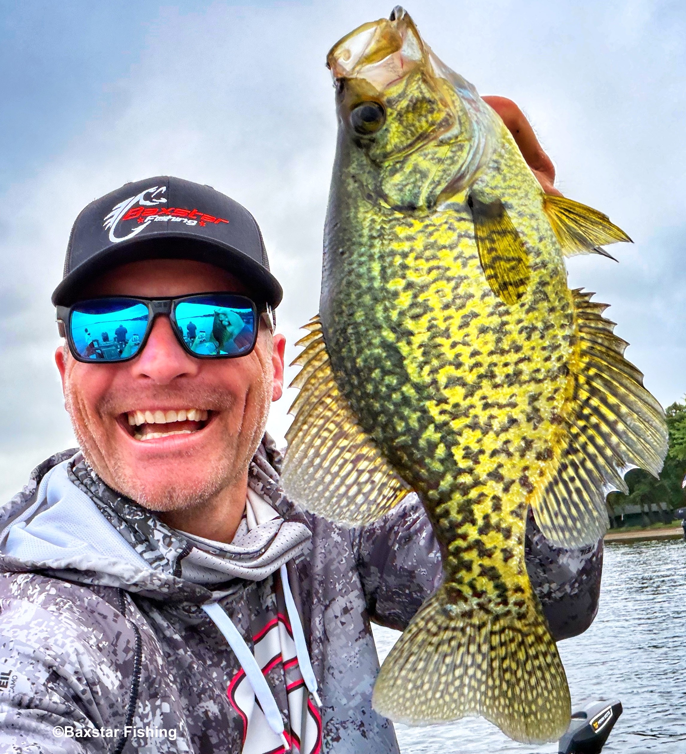 Man holding up a huge crappie fishing from his boat