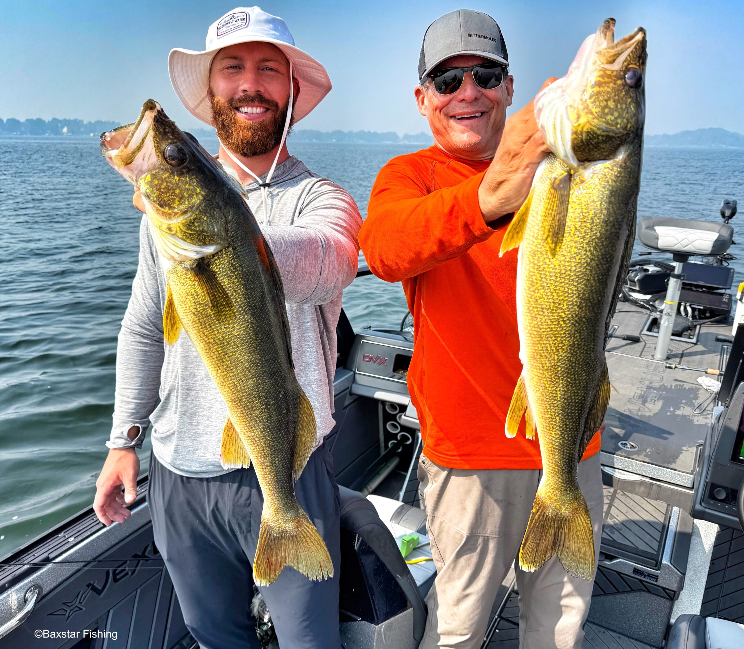 Two men in a boat on a lake holding up two nice walleyes they caught