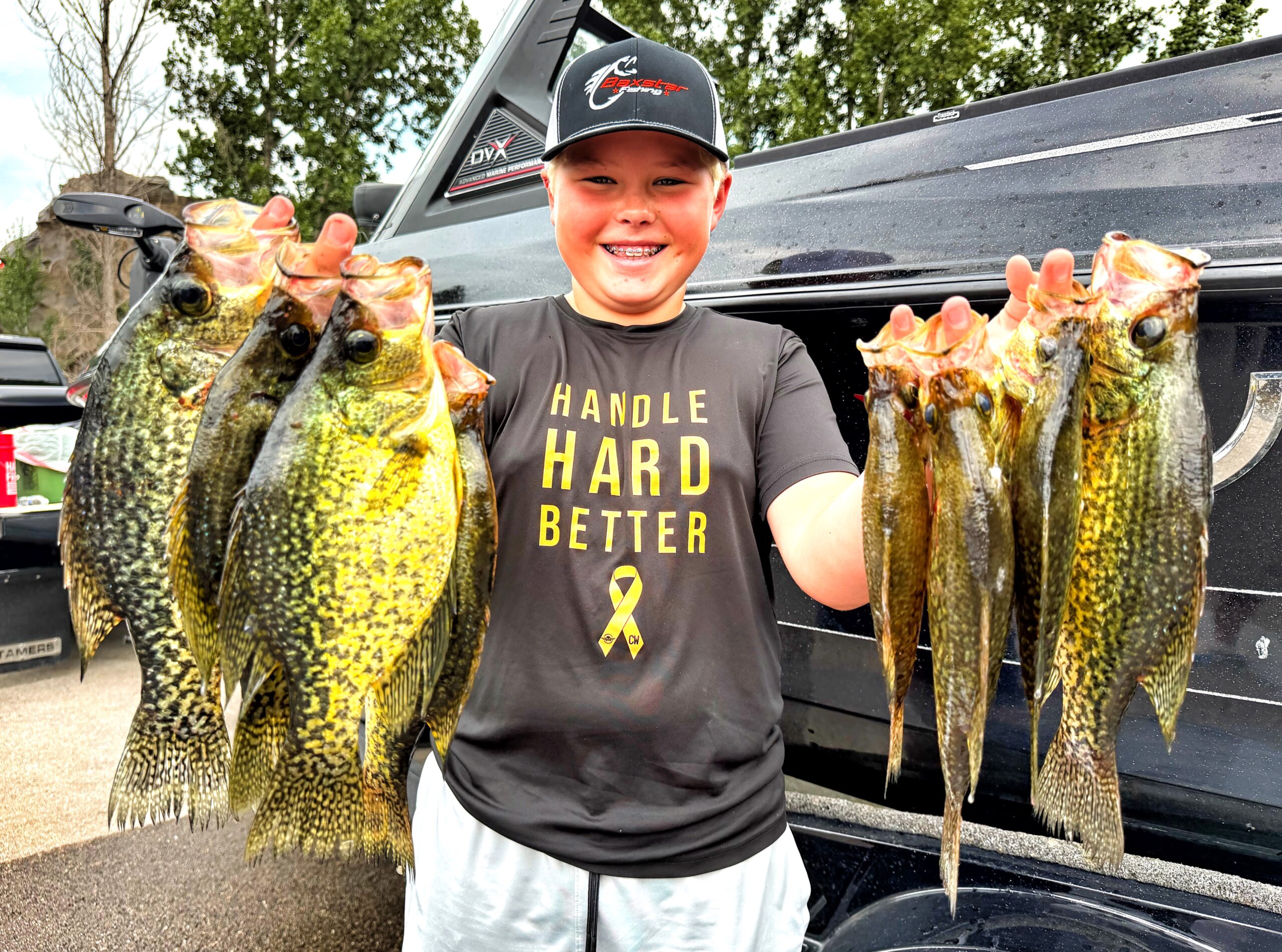 smiling boy holding a stringer of crappies