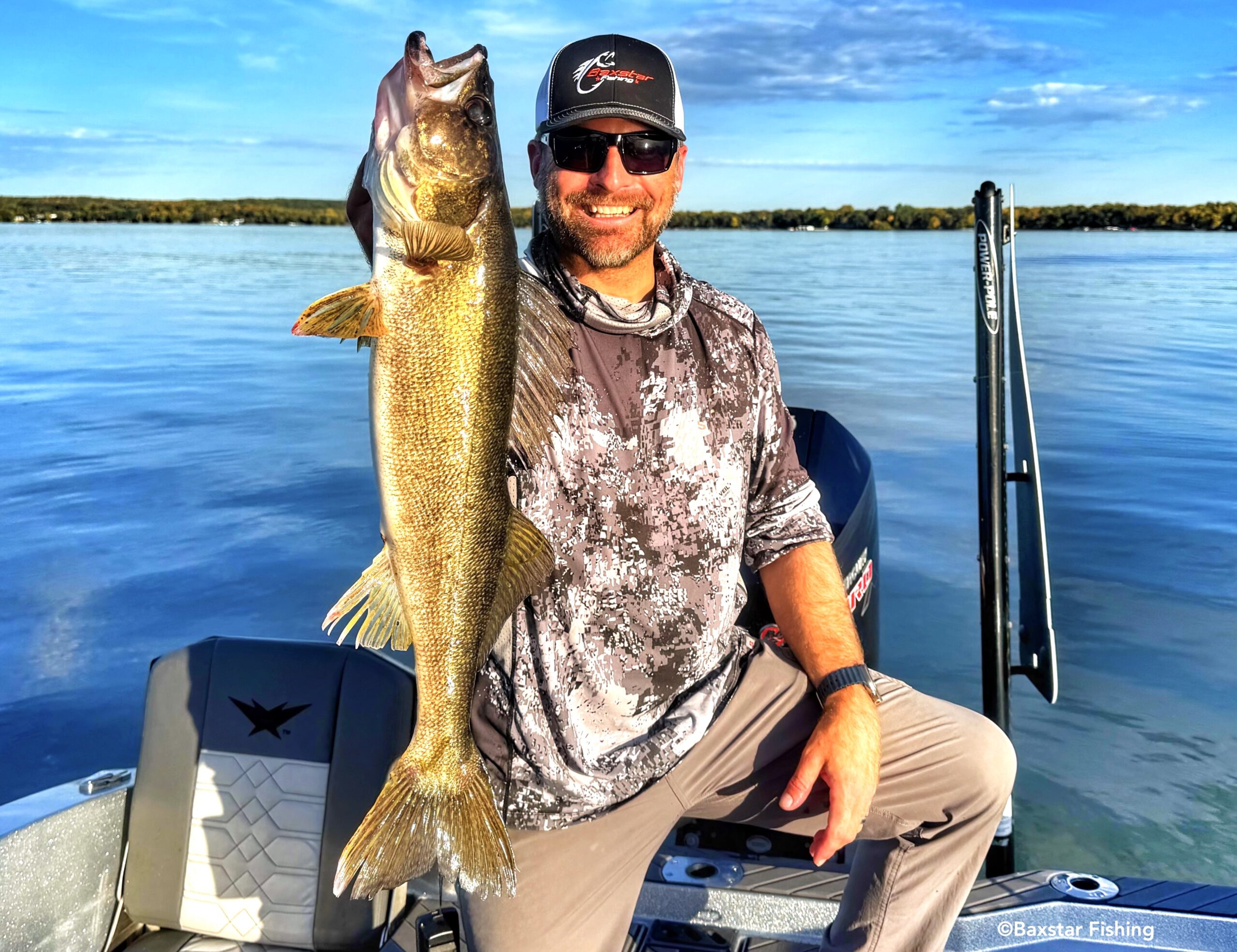 man holding a really nice walleye he caught while fishing in a boat