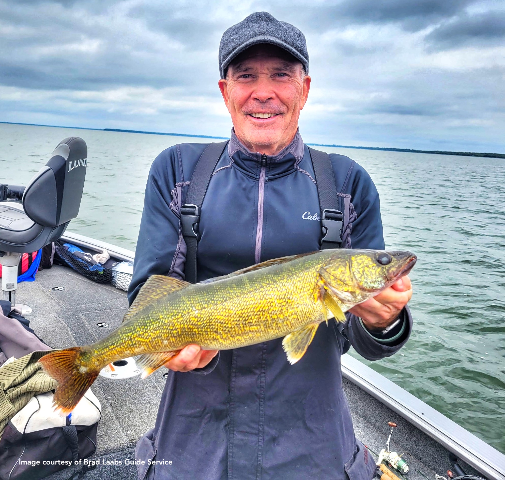 man holding a nice walleye he caught in a boat on the lake